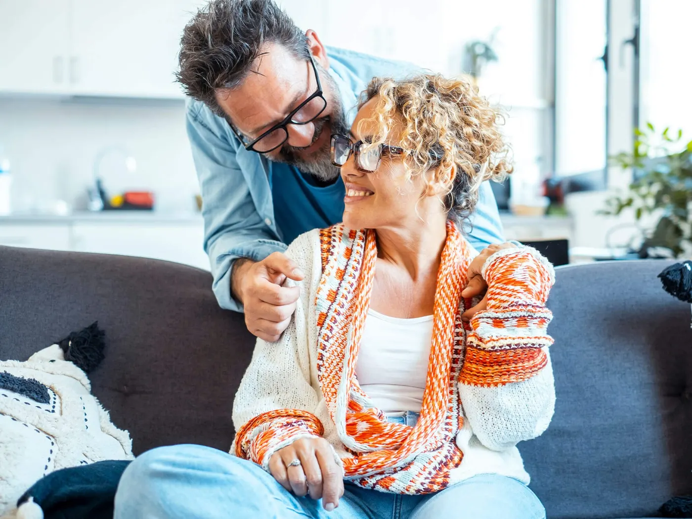 Smiling middle-aged couple sharing a relaxed moment on a sofa