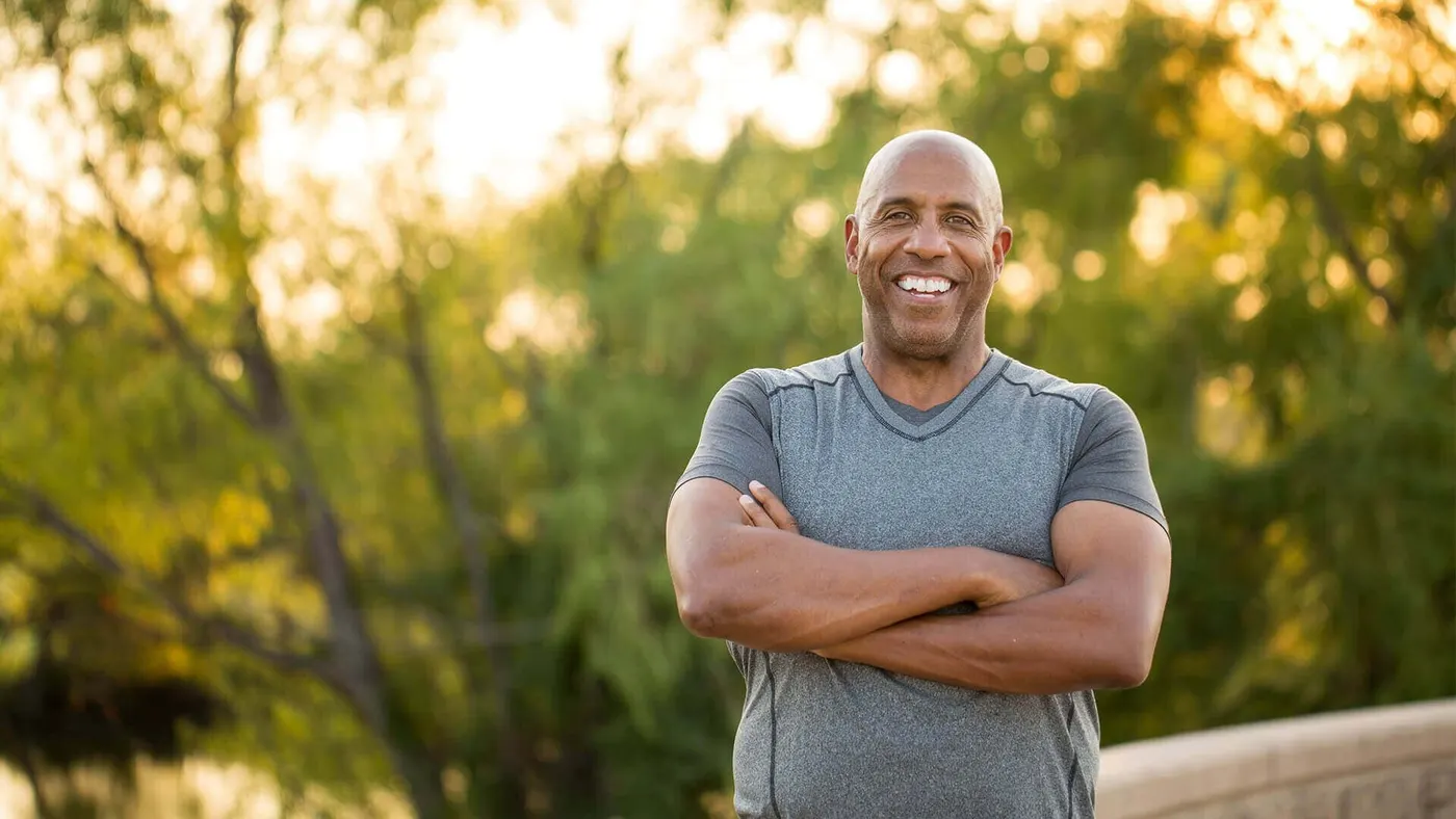 Smiling man standing outdoors with his arms crossed