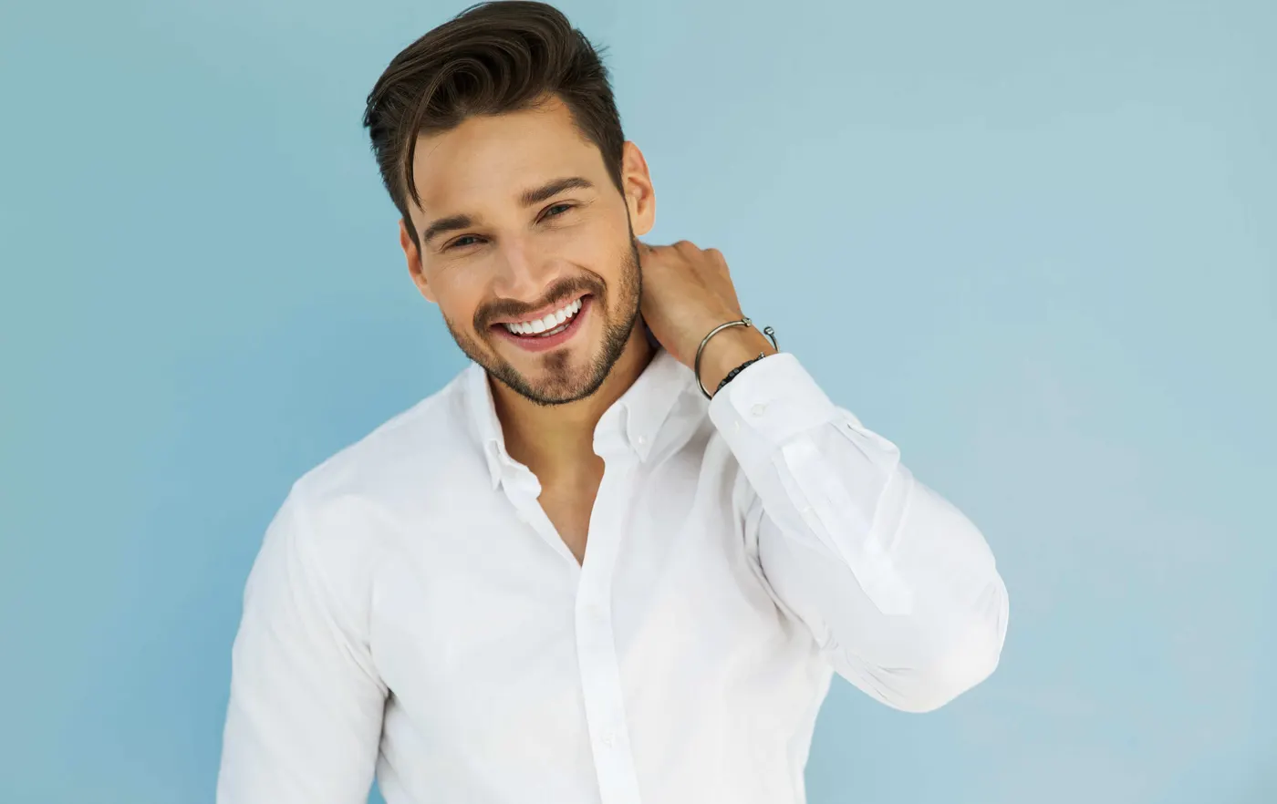 Smiling man in a white shirt against a blue wall