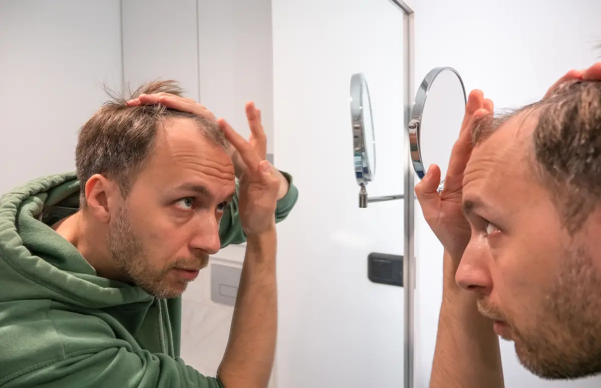 Balding man checking his hair in a mirror