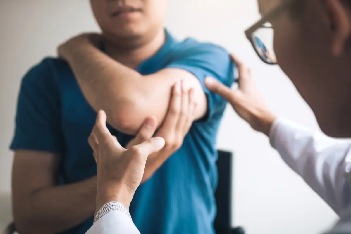 Clinician examining a man's elbow