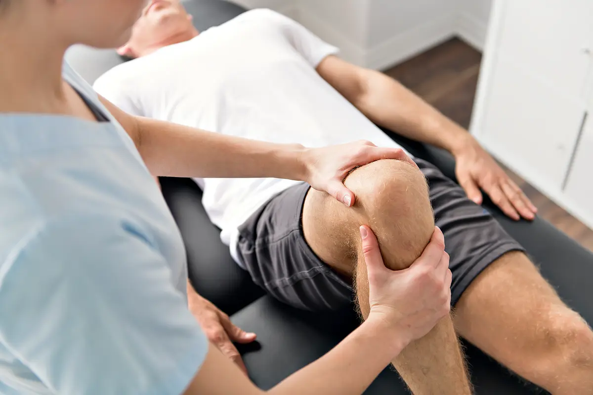 Clinician examining a man's knee