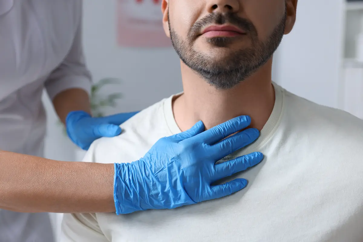 Clinician examining a man's neck and thyroid