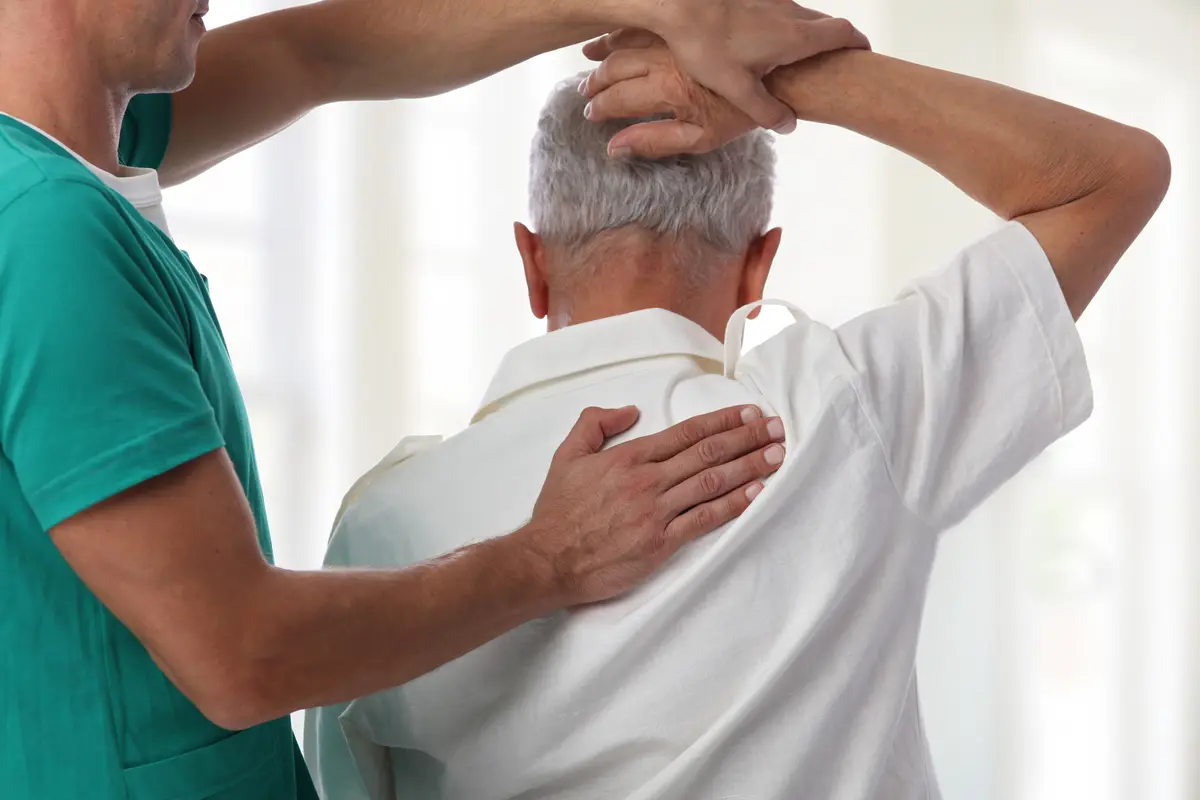 Clinician examining an older man's shoulder
