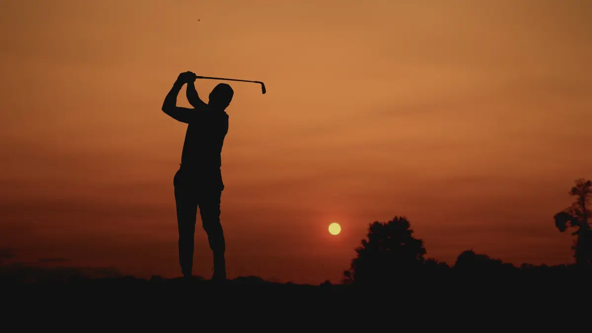 Golfer silhouetted against a sunset