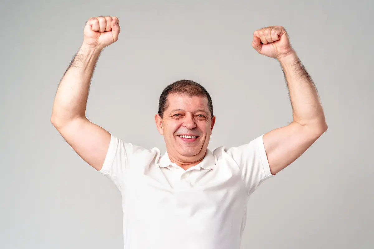 Happy older man raising both arms