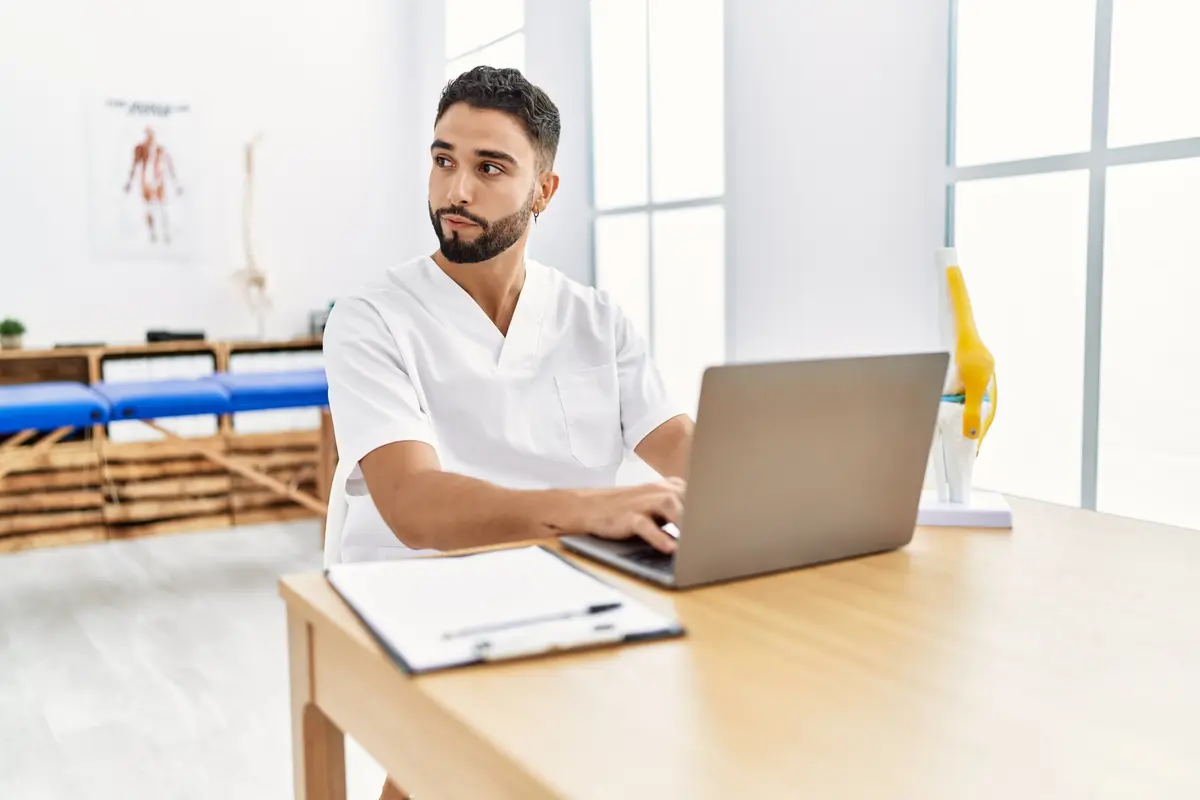 Male clinician working at a laptop in a clinic