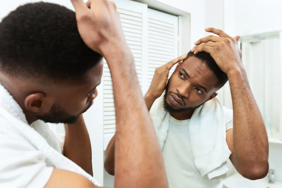 Man checking for thinning hair in a mirror