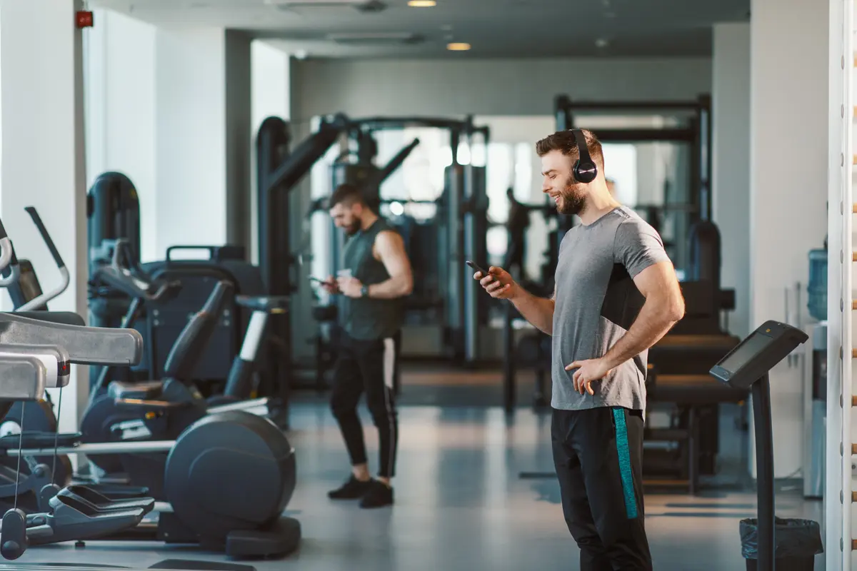 Man checking his phone in a quiet gym