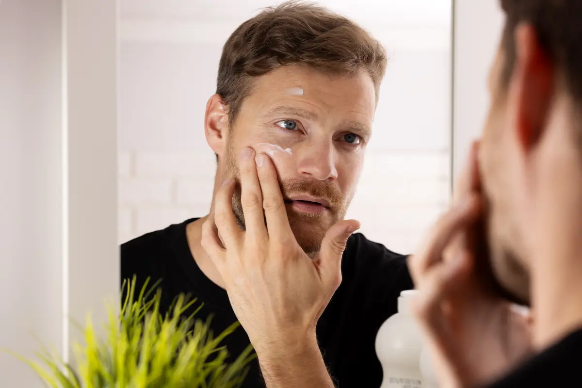 Man checking the skin on his face in a mirror