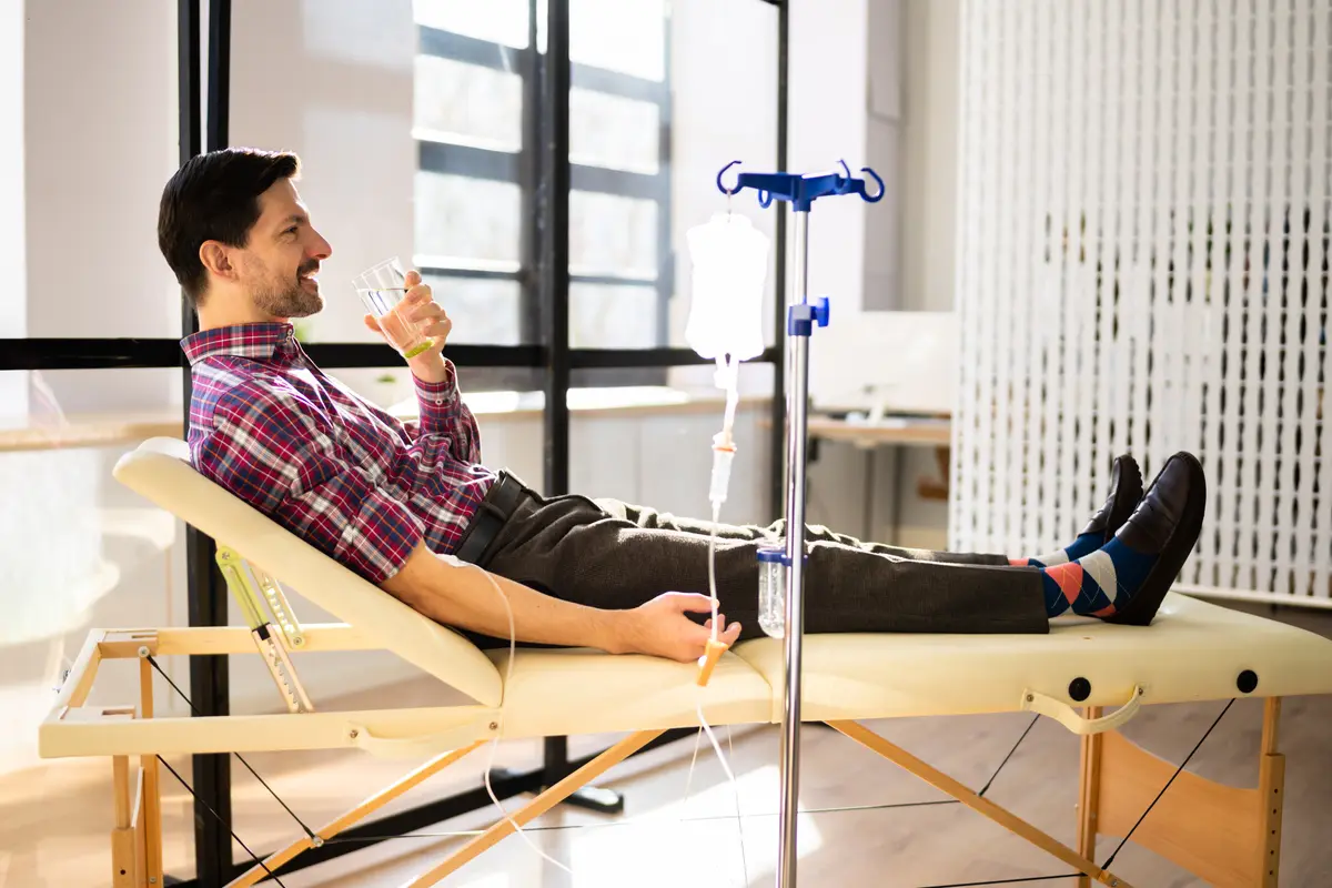 Man drinking water while reclining during an IV drip
