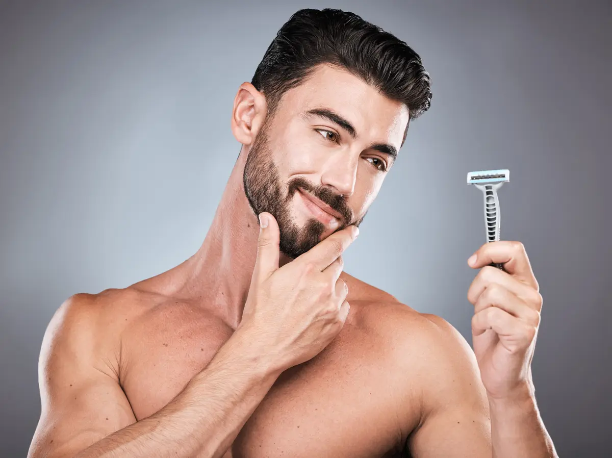 Man holding a razor and checking his jawline