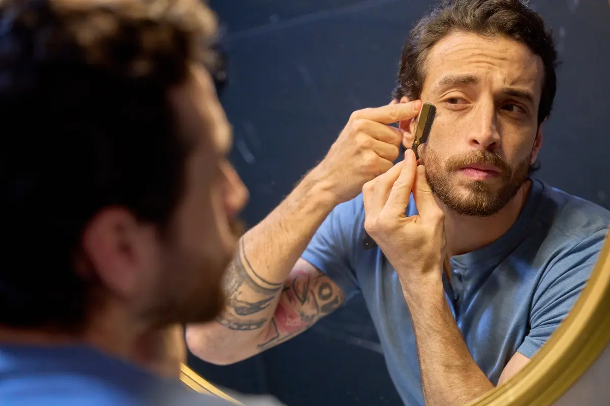 Man looking closely at his skin in a hand mirror