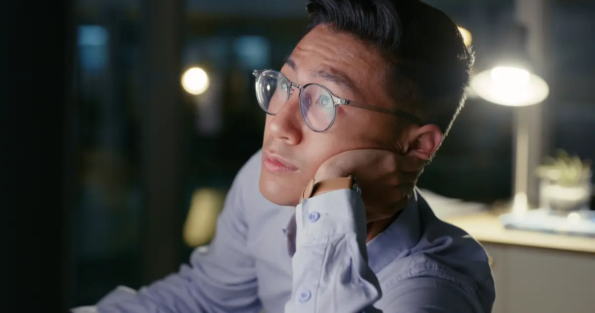 Man lost in thought at his desk at night