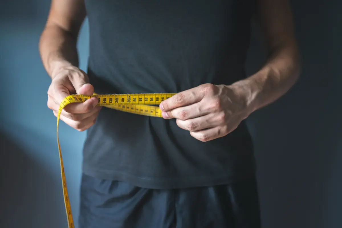 Man measuring his waist with a tape measure