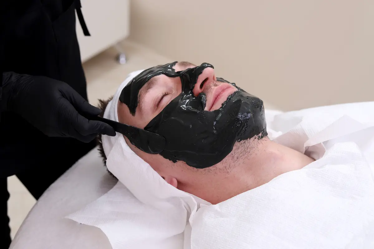 Man relaxing with a charcoal facial mask