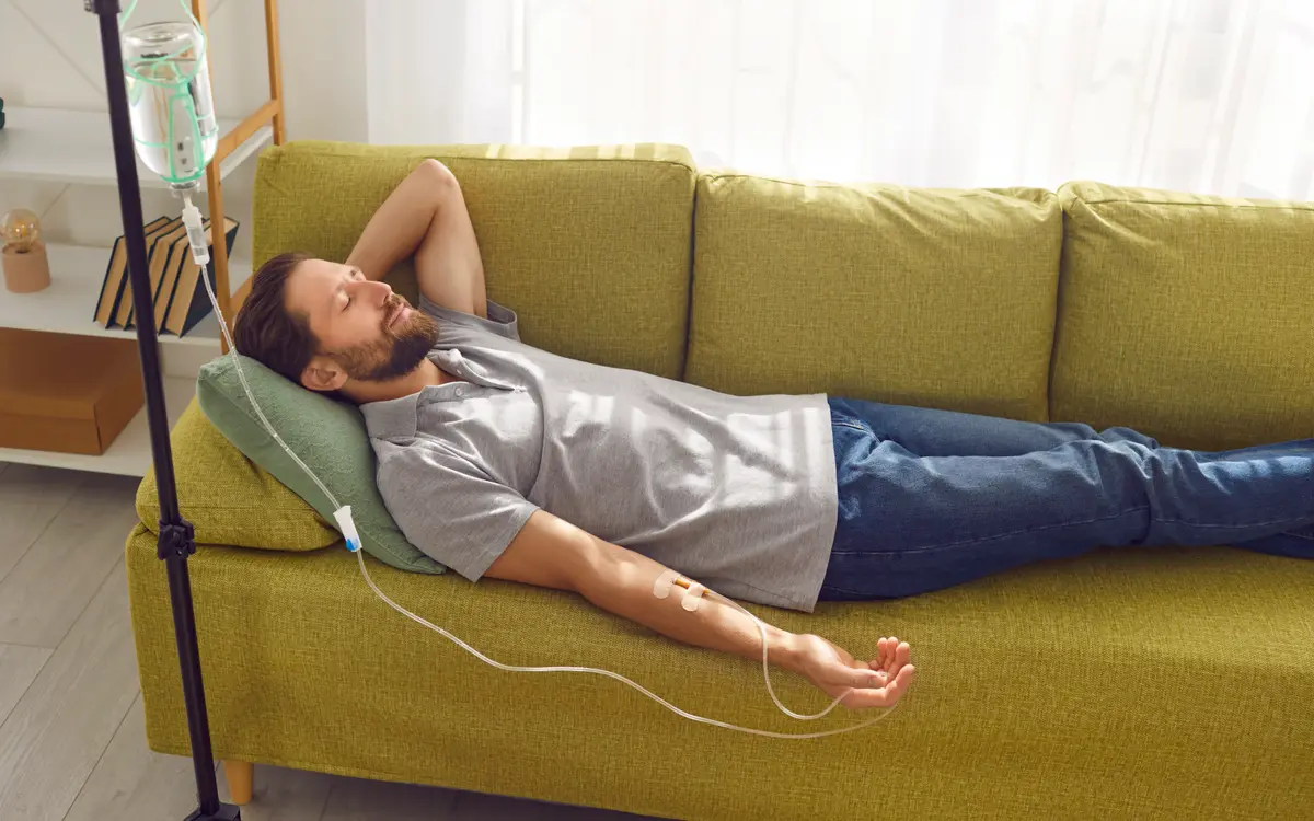 Man resting on a couch during an IV drip