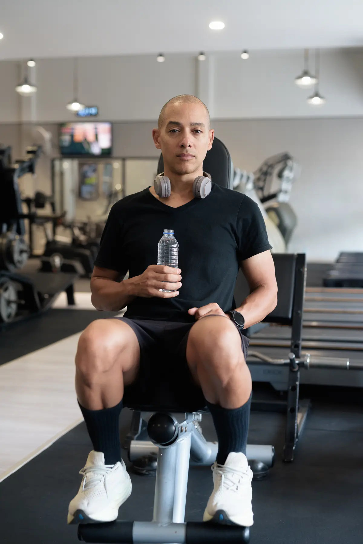 Man resting on a gym bench with a water bottle