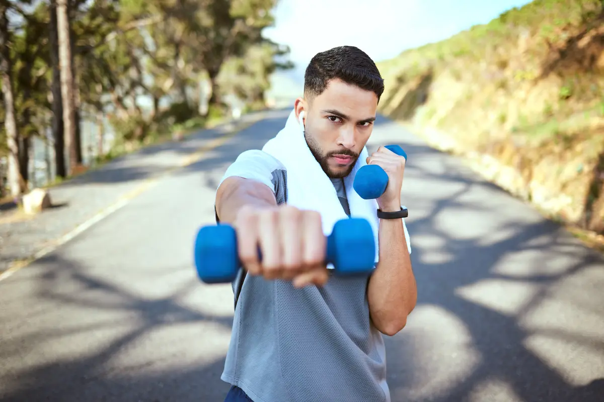 Man shadowboxing with dumbbells outdoors