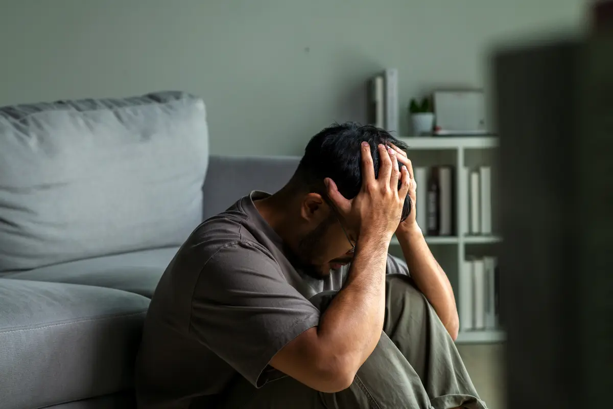 Man sitting on a couch with his head in his hands