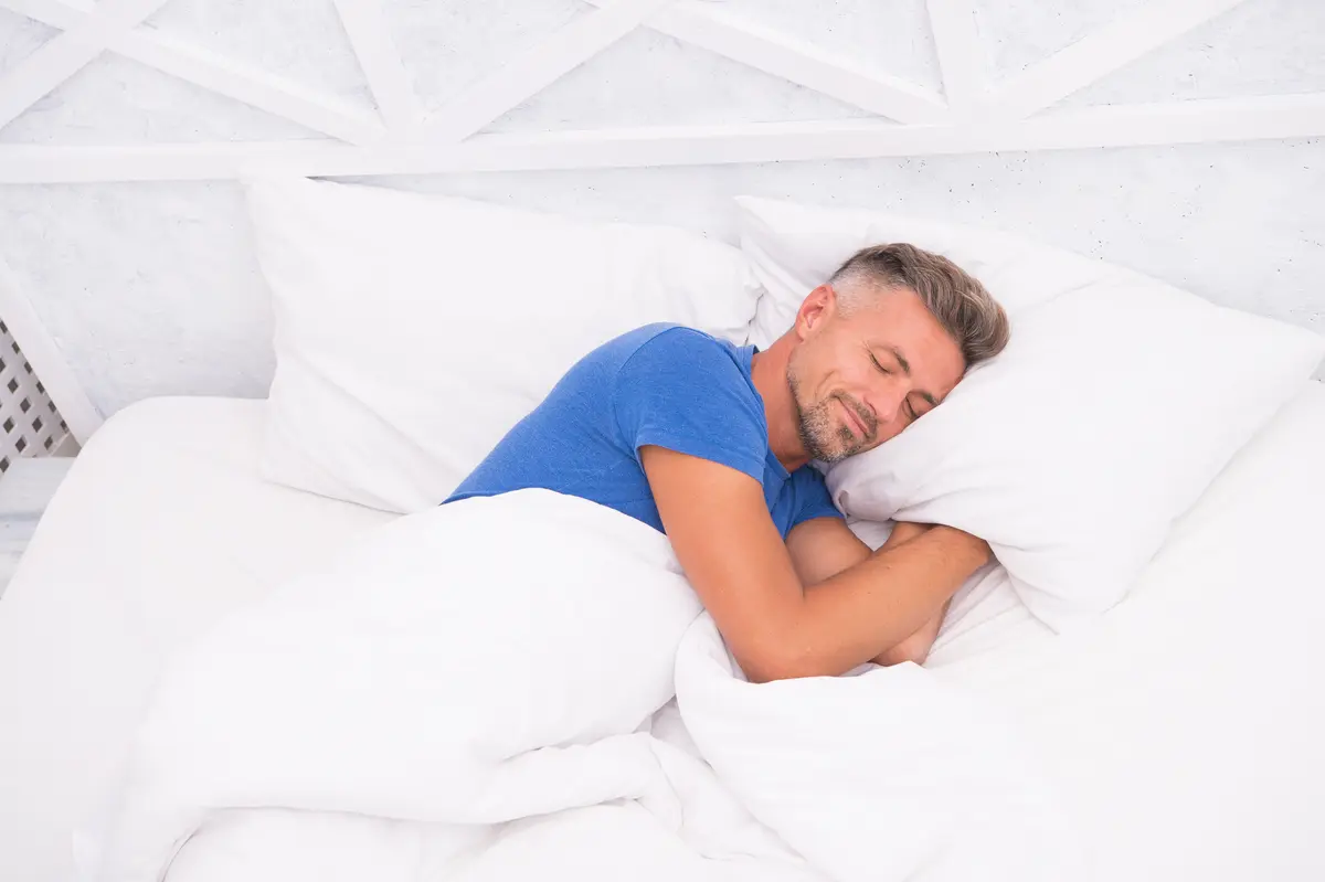 Man sleeping soundly in white sheets