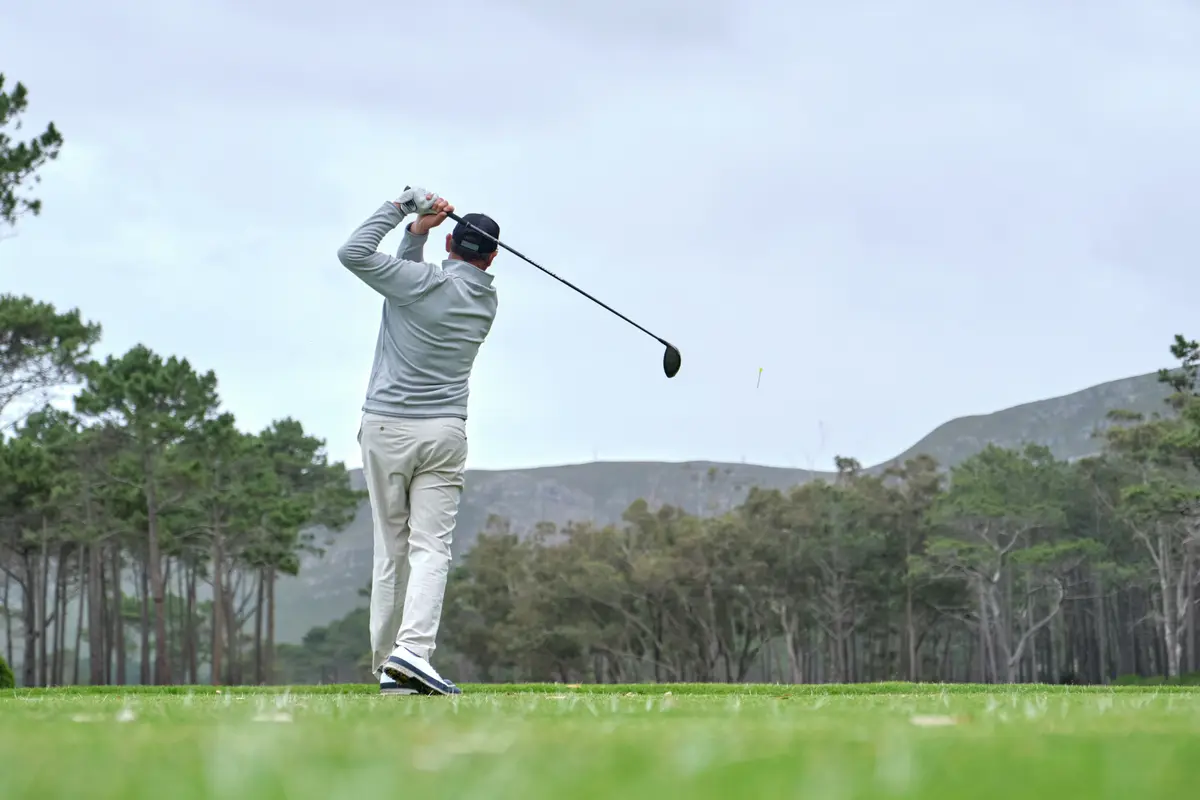Man swinging a golf club on a course