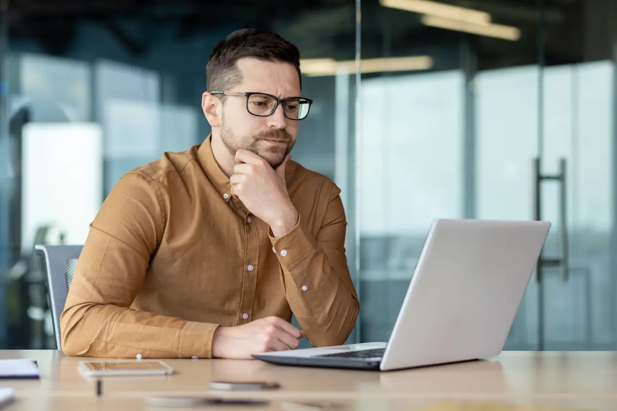 Man thinking at his laptop in an office