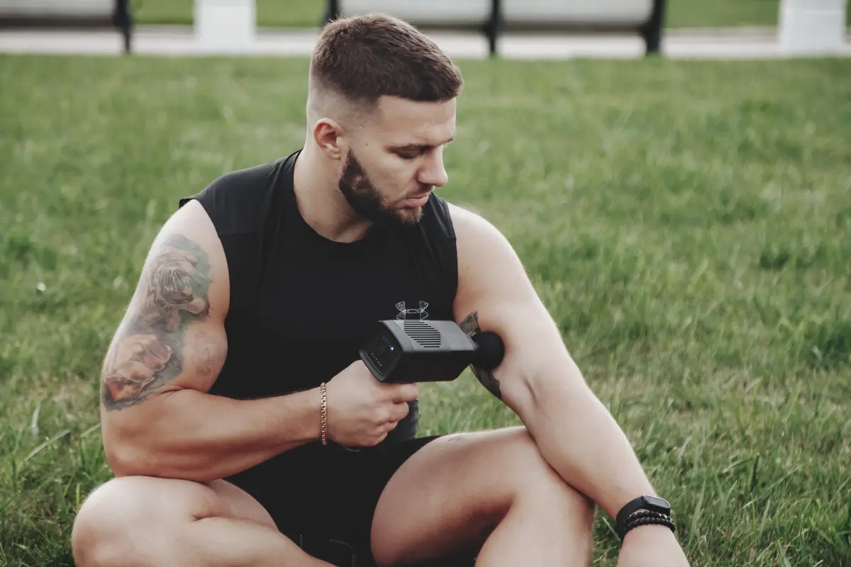 Man using a massage gun on his arm