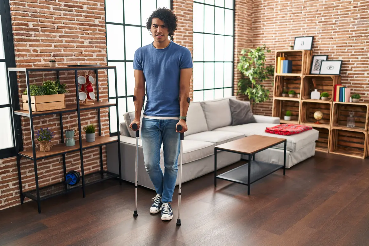Man walking with crutches at home