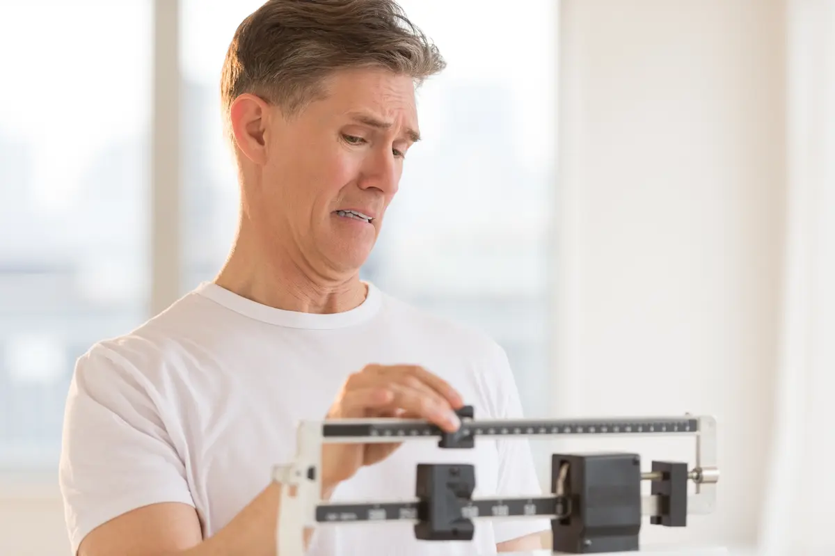 Man weighing himself on a balance scale