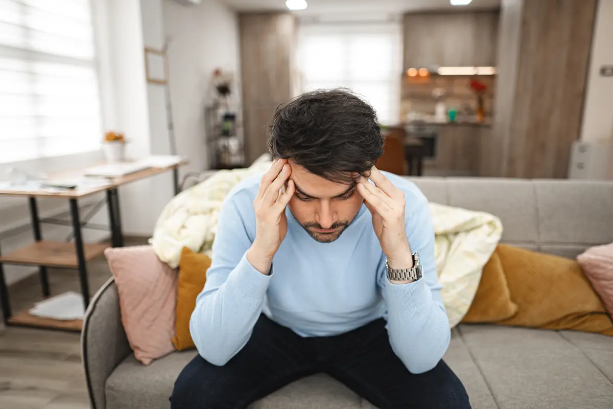 Man with a headache sitting on a couch