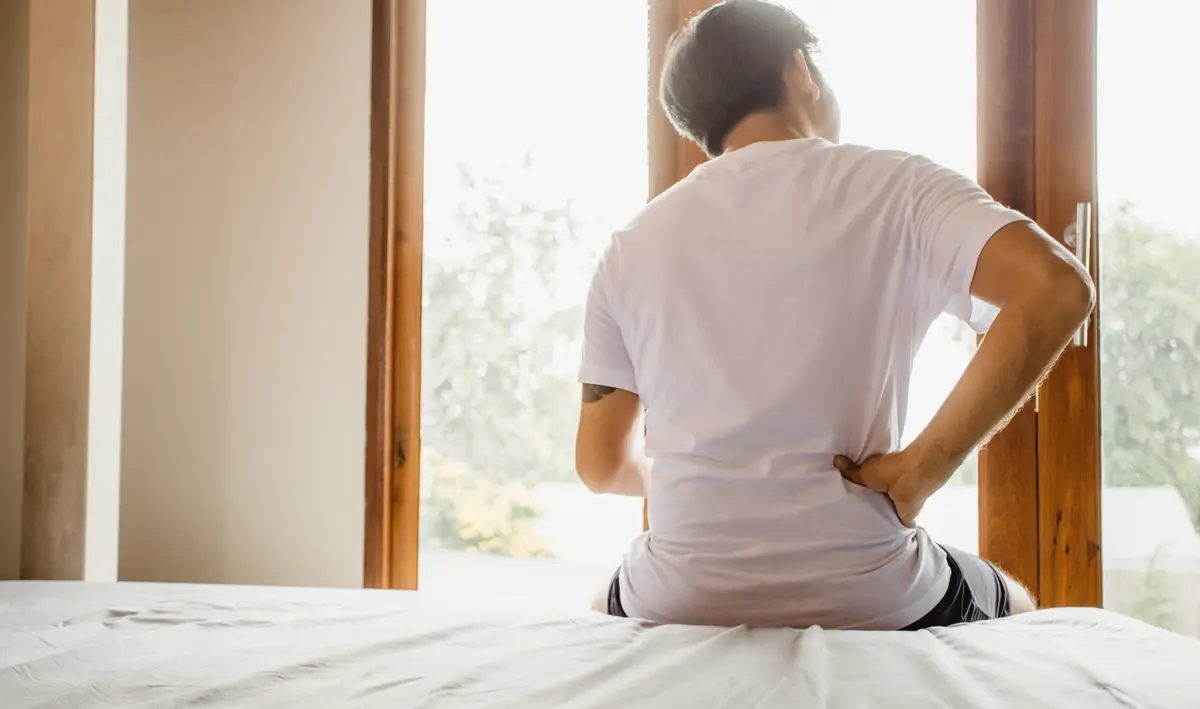 Man with back pain sitting on a bed