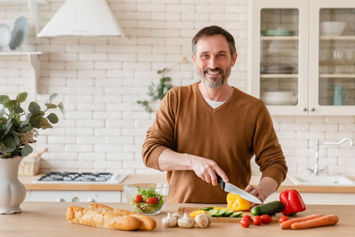 Middle-aged man cooking vegetables in his kitchen