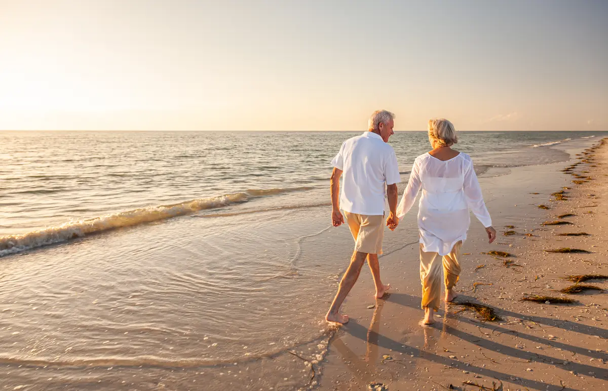 Older couple walking on the beach at sunset