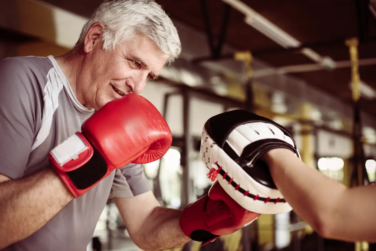 Older man boxing with pads in a gym