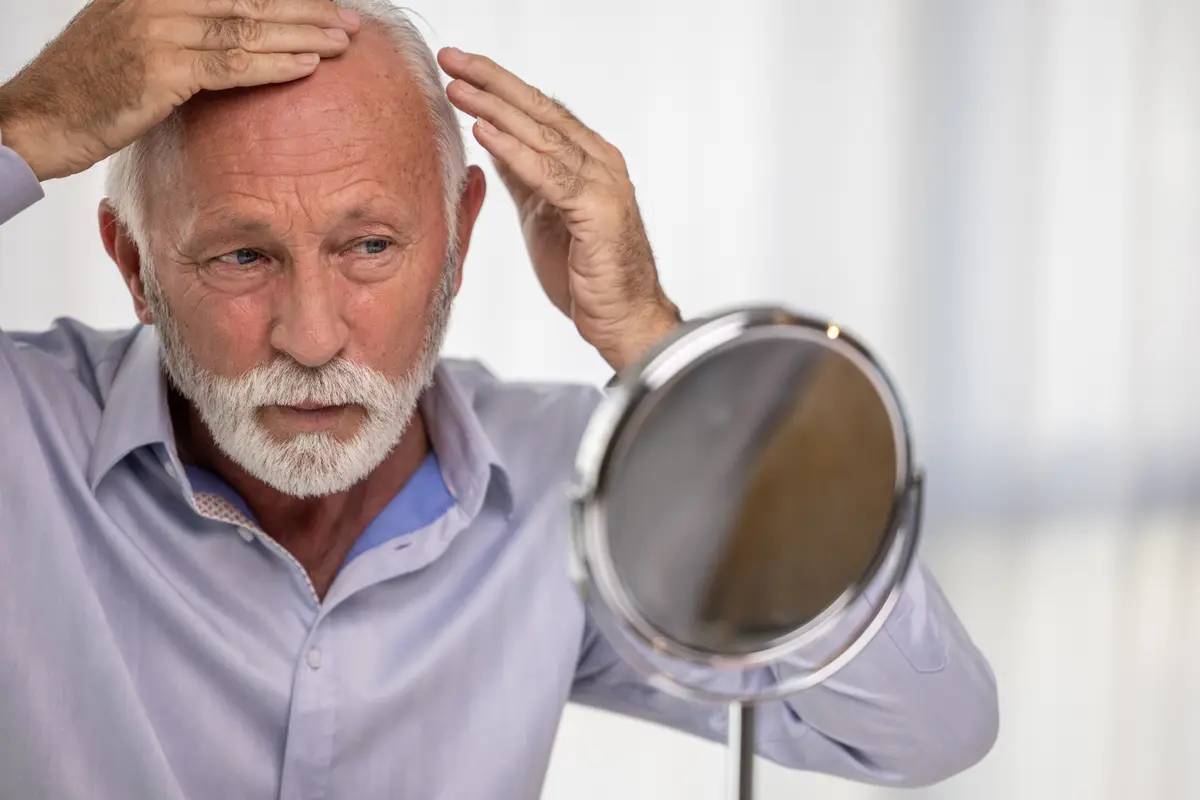 Older man checking his hairline in a mirror