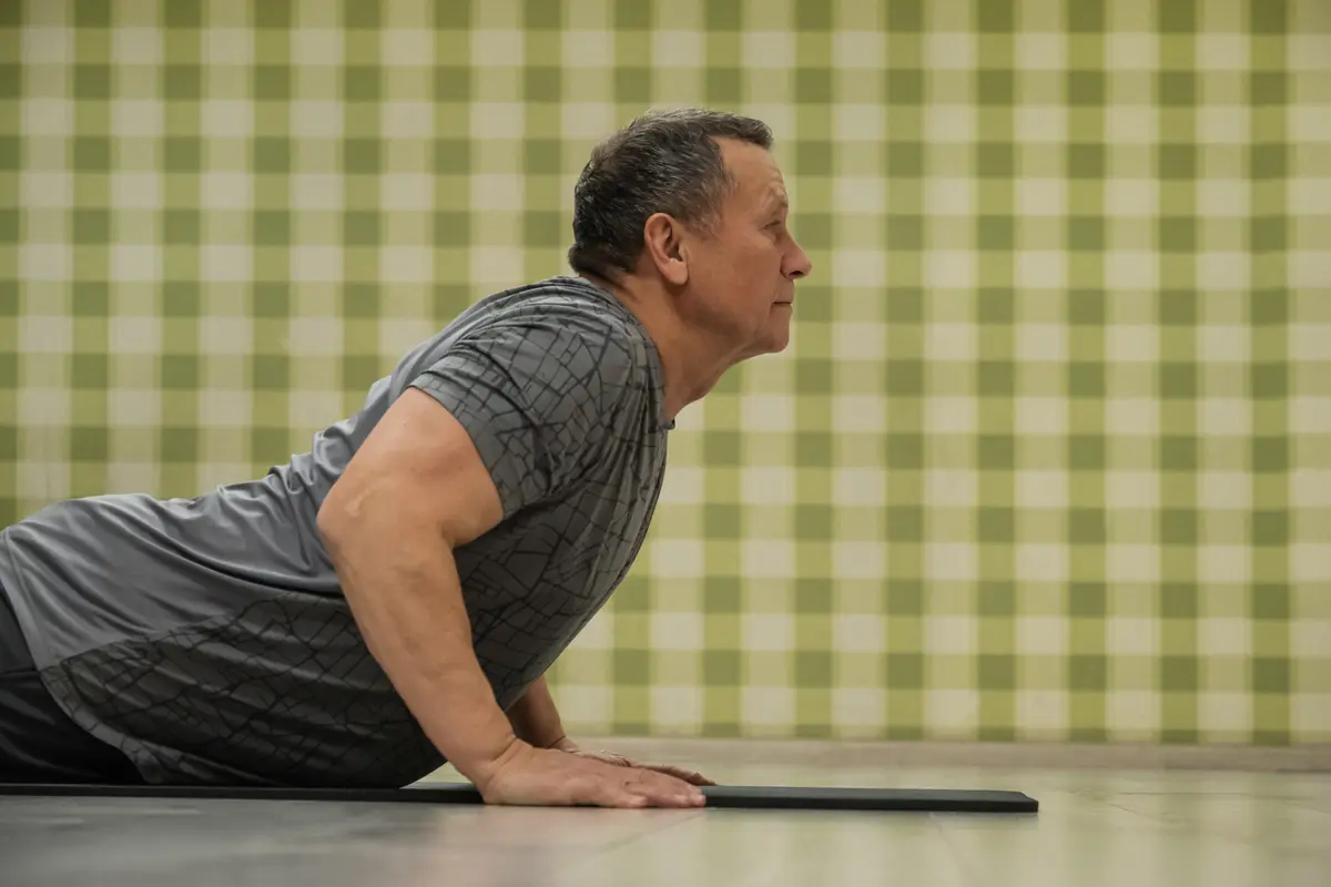 Older man doing push-ups on a mat at home