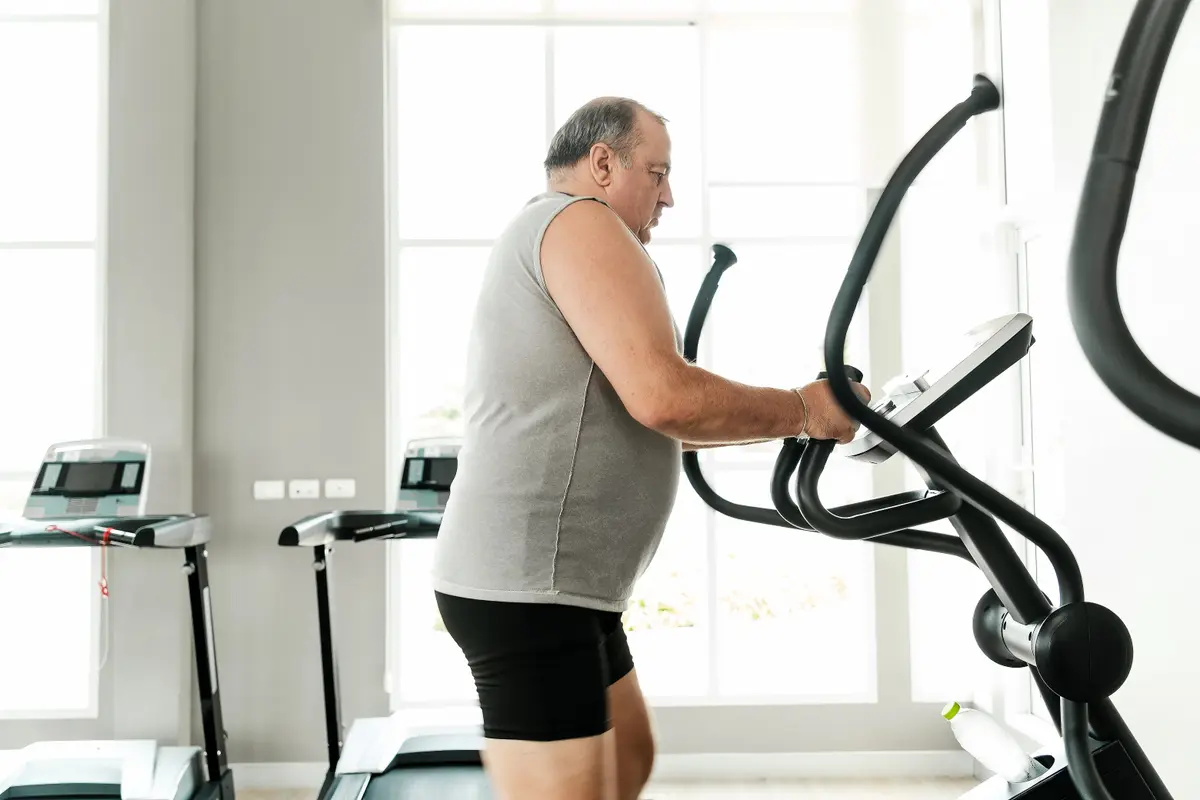 Older man exercising on an elliptical at home