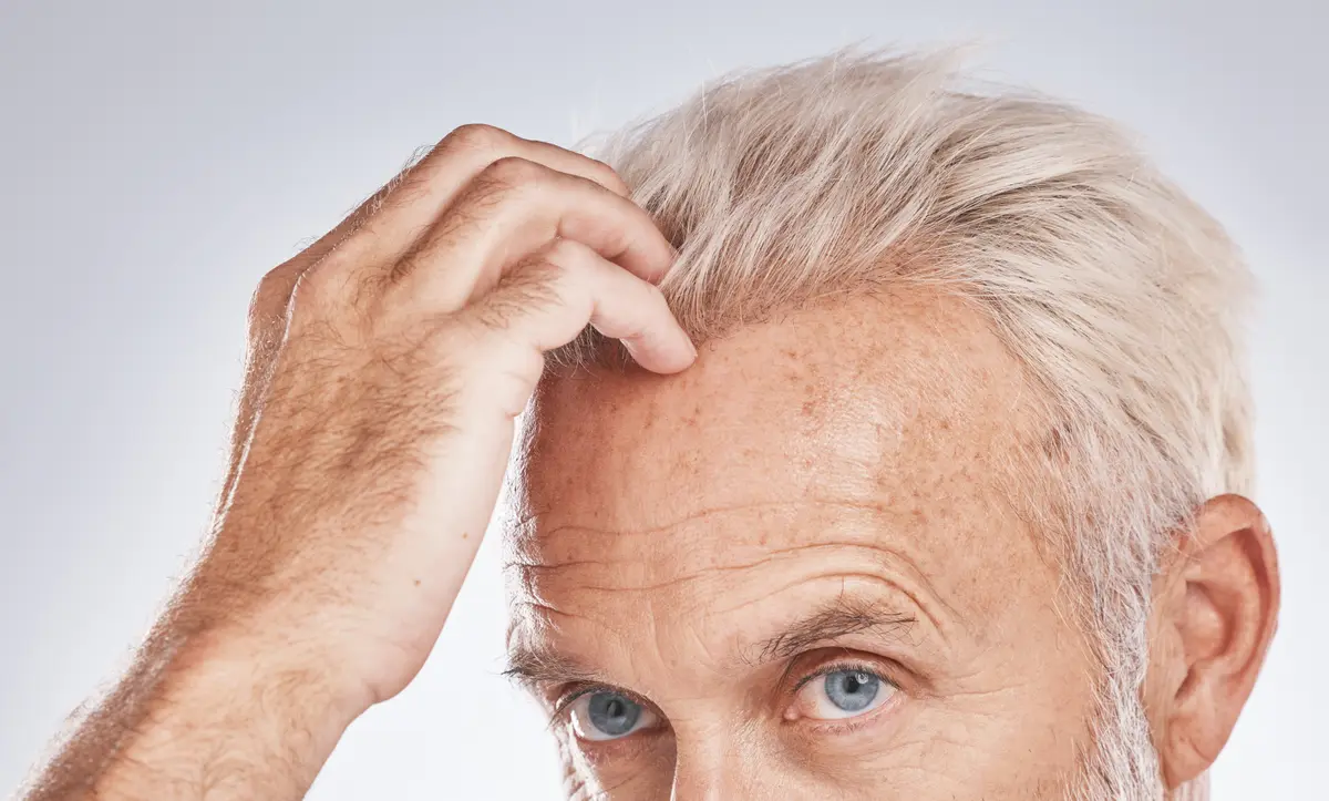 Older man touching his hairline