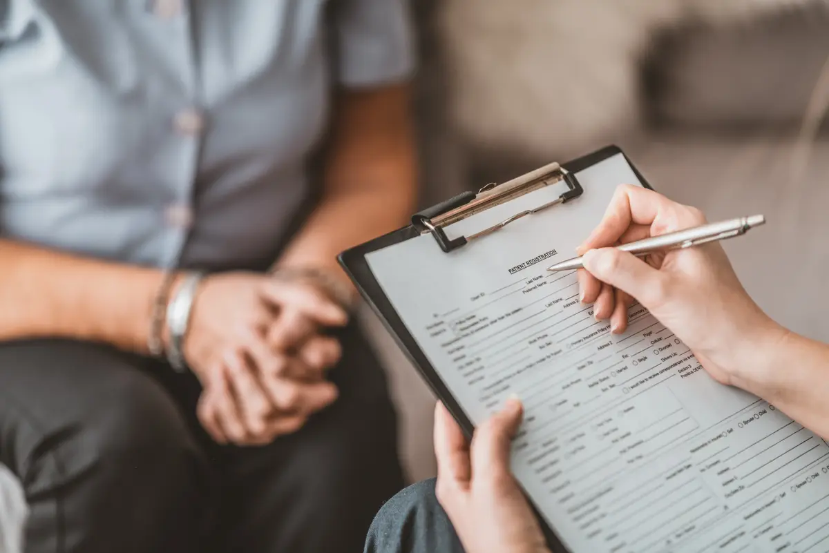 Patient filling out an intake form on a clipboard