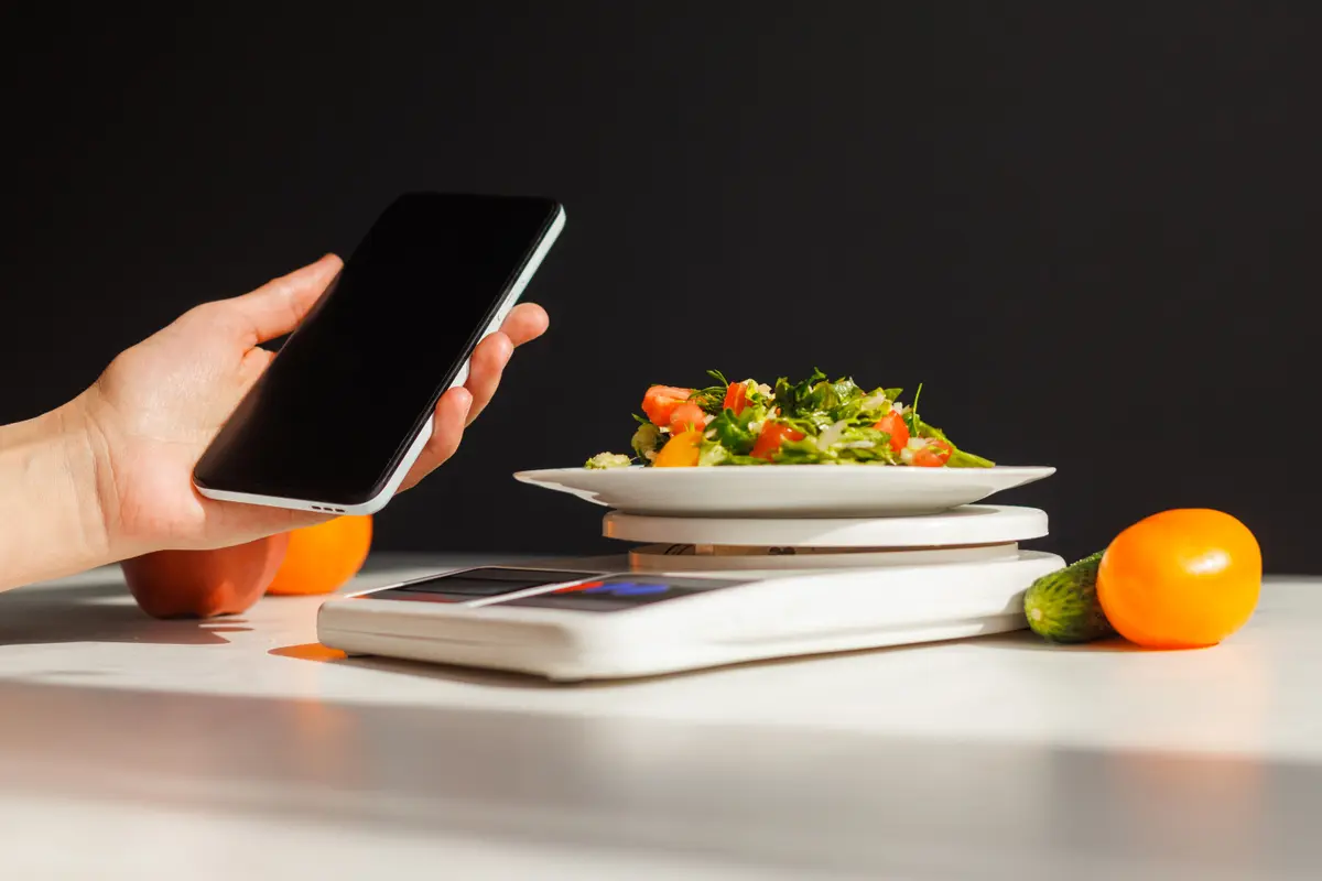 Phone, salad and fruit on a kitchen scale