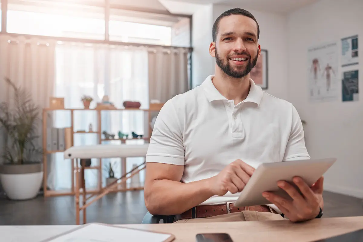 Smiling male clinician holding a tablet