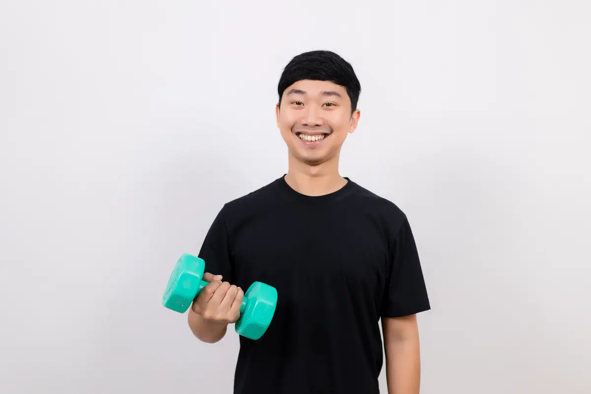 Smiling man holding a light dumbbell