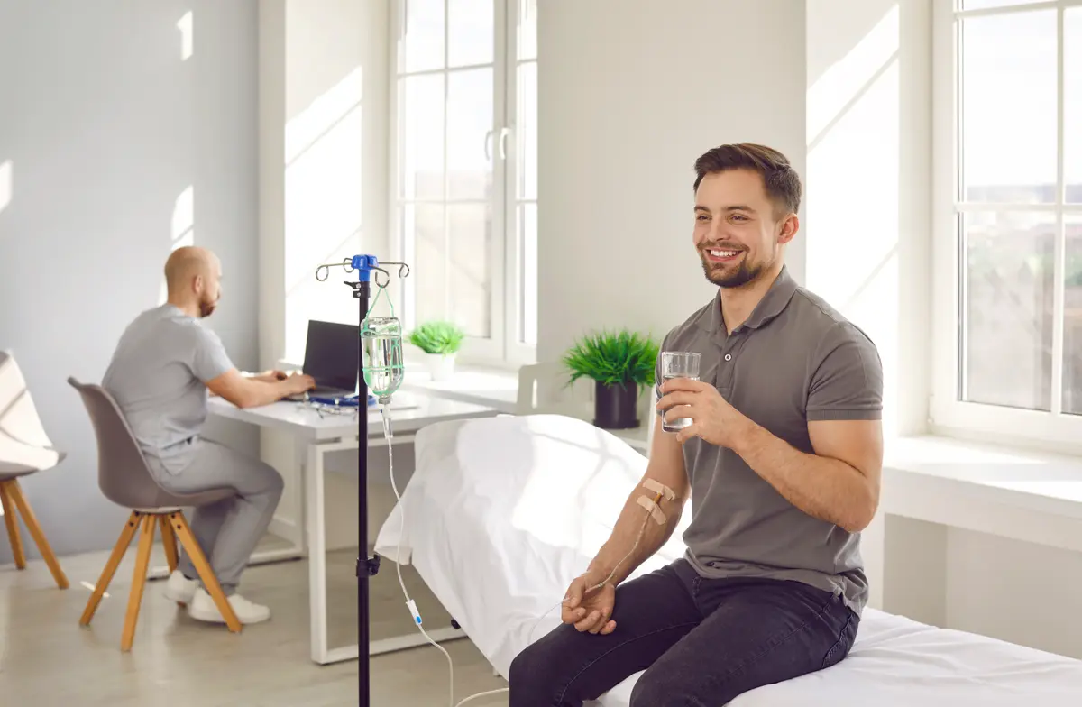 Smiling man receiving an IV drip in a clinic