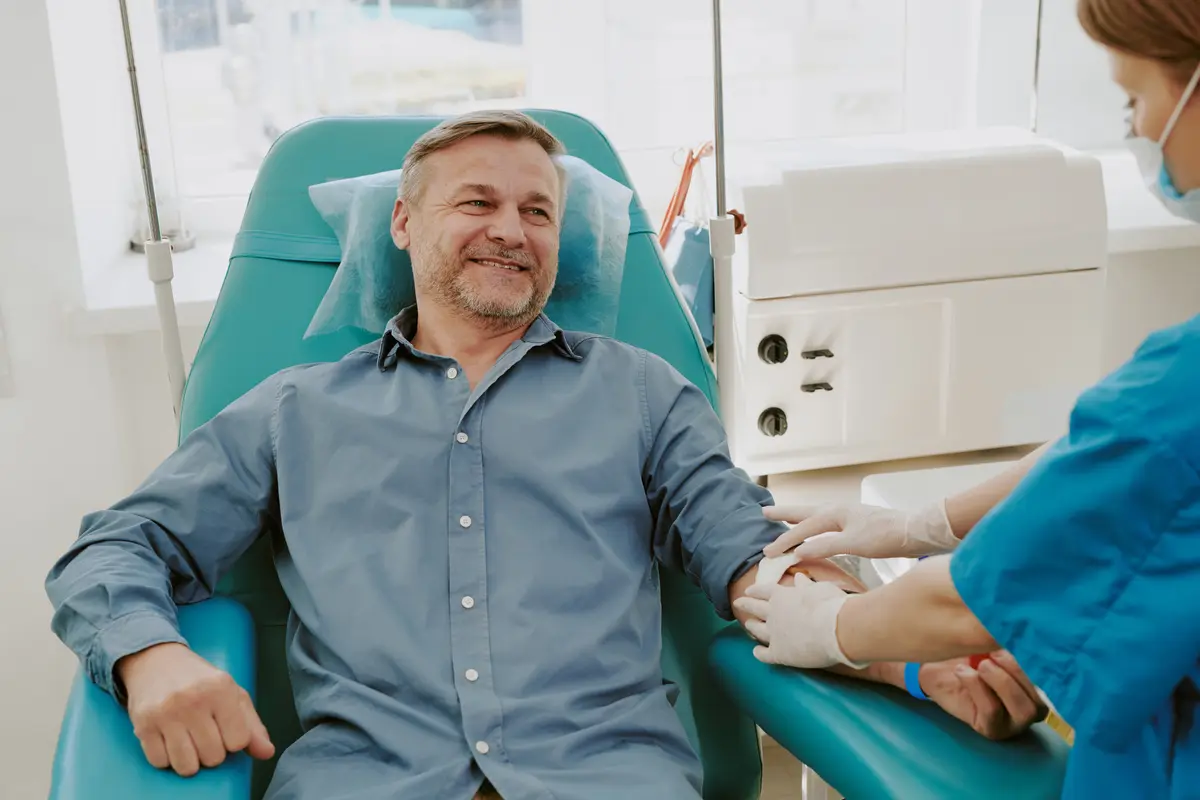 Smiling middle-aged man having blood drawn at a clinic