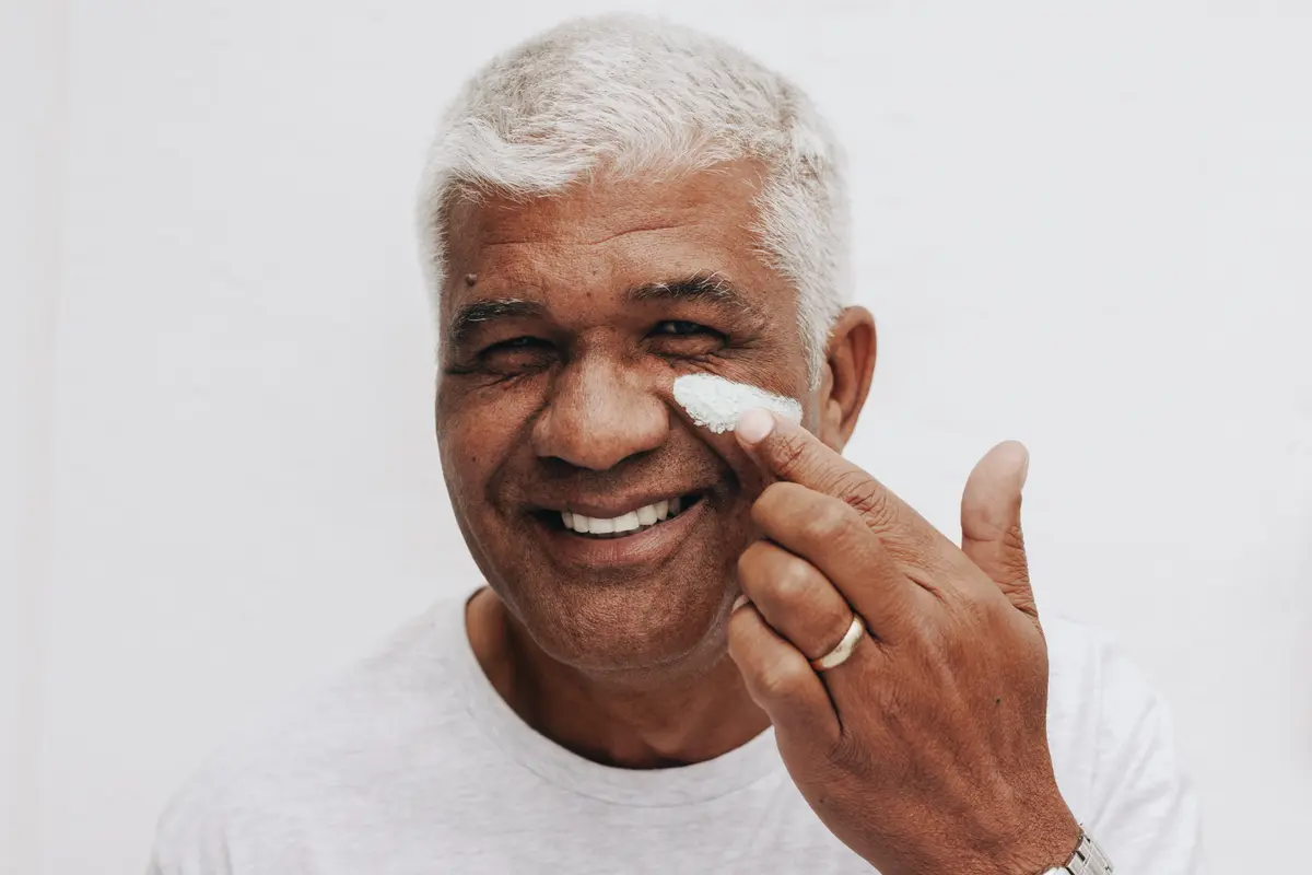 Smiling older man applying moisturizer