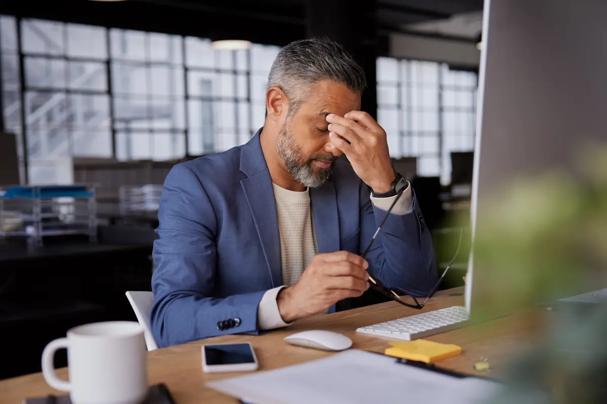 Stressed businessman rubbing his eyes at his desk