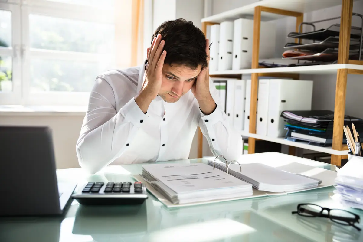 Stressed man holding his head at his desk