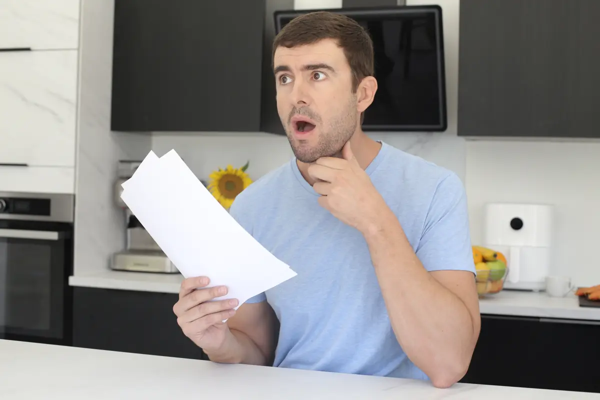 Surprised man reading a bill in his kitchen
