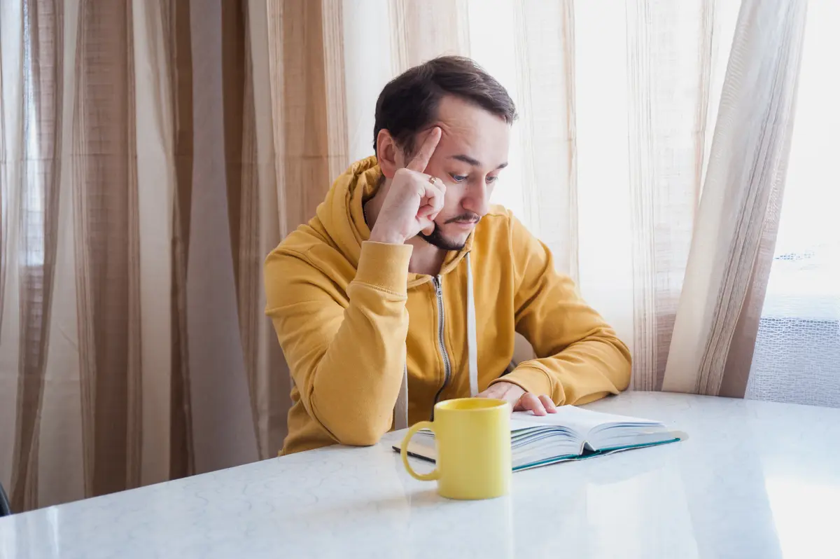 Tired man resting his head on his hand over coffee